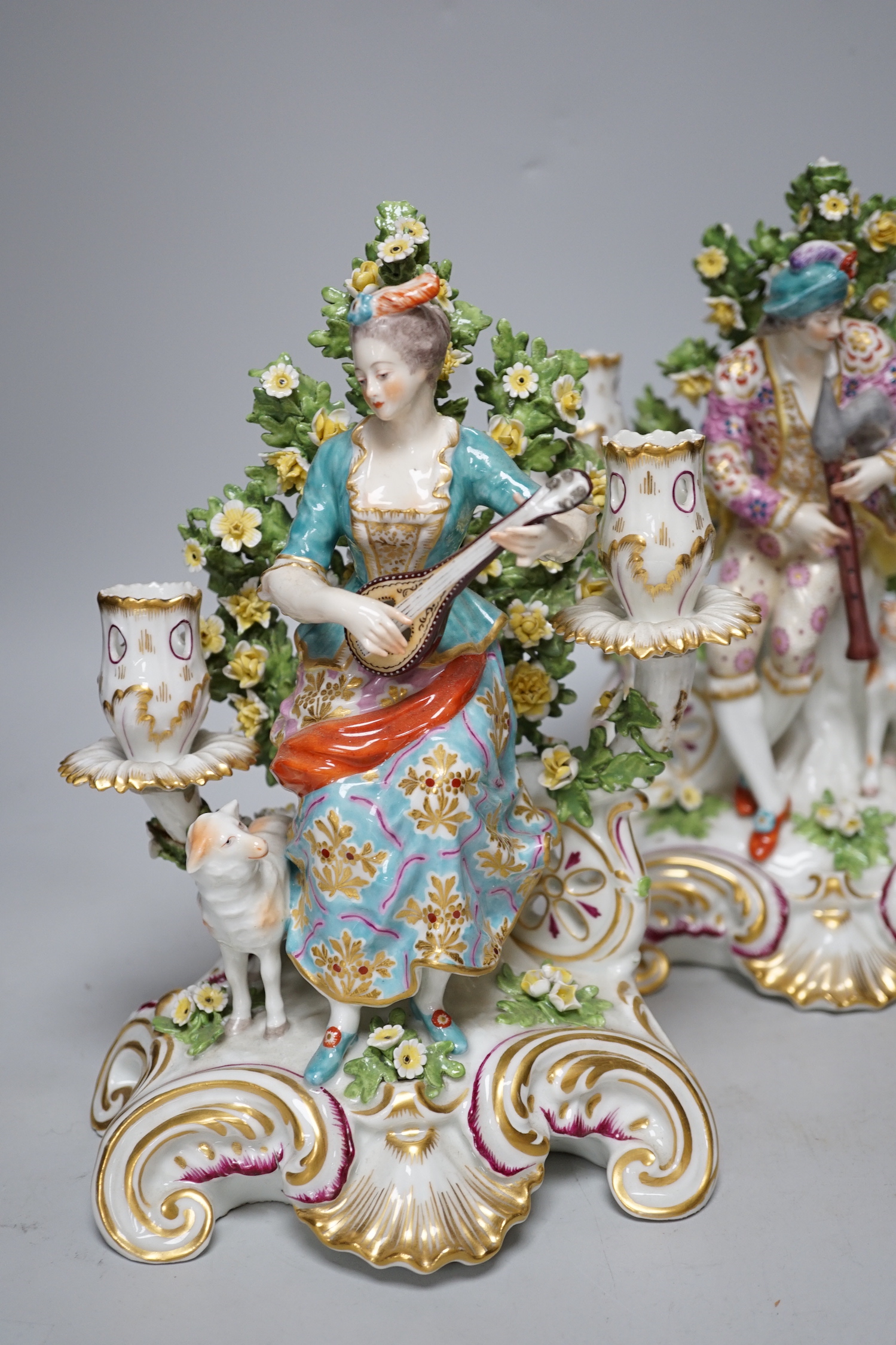 A pair of French porcelain two branch figural candlesticks in the form of musicians, largest 29cm high
